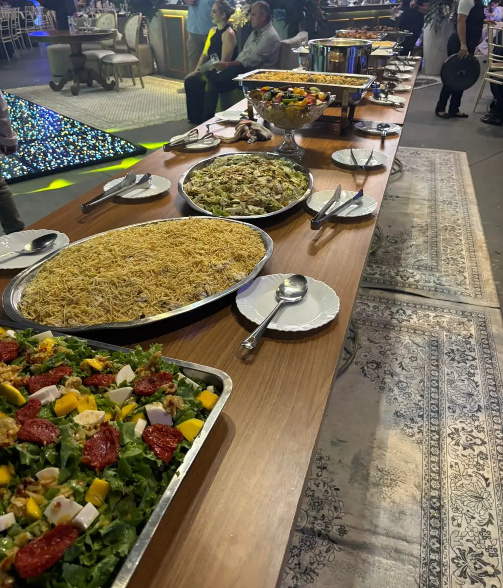 Mesa do buffet com salada verde com manga e tomate seco, maionese com batata palha e salada de frutas